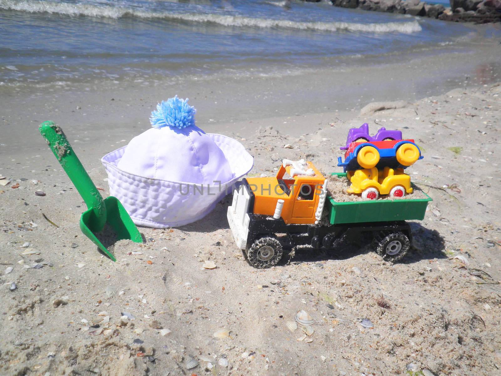 Children's toys and hat on beach by NickNick
