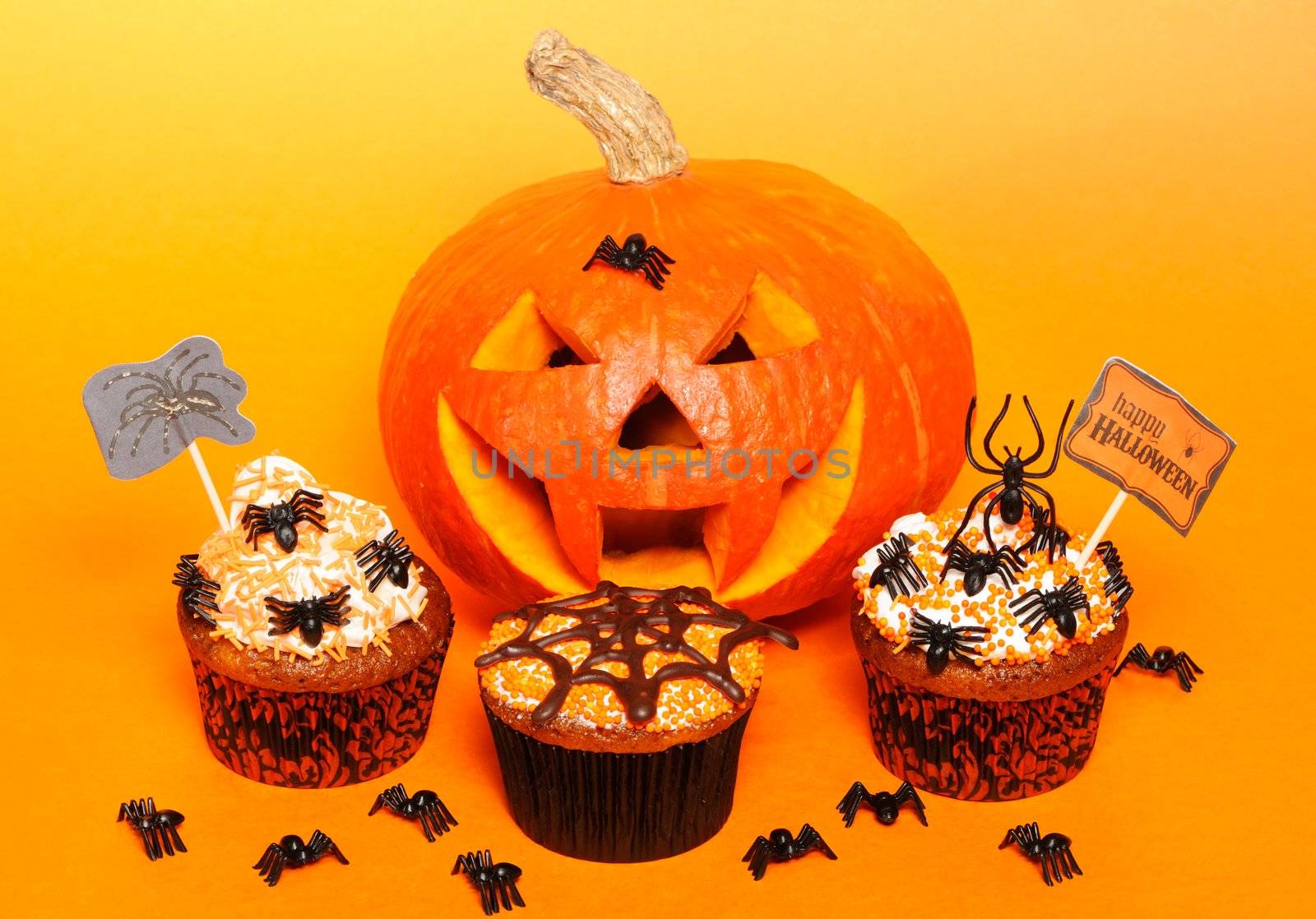 Halloween cupcakes with decoration over orange background