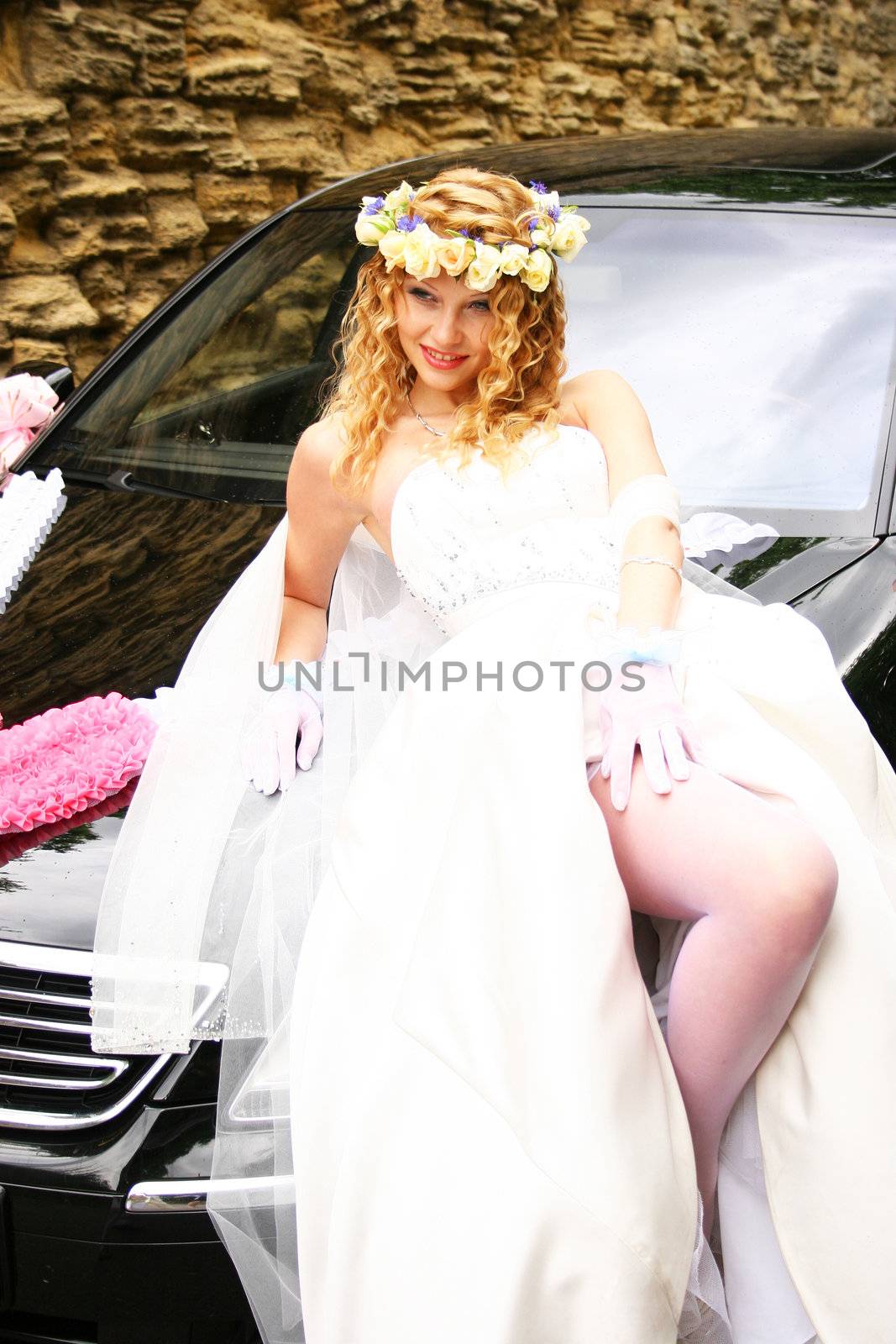 Bride posing near a car
