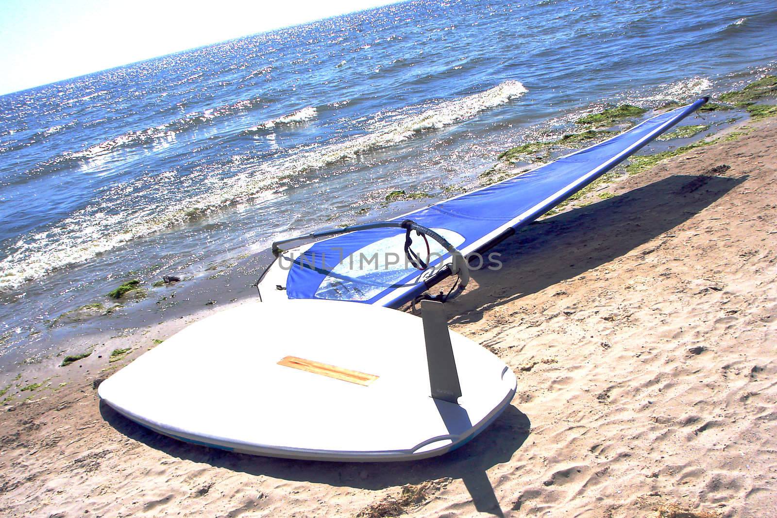 Board and sail for windsurfing on the beach by NickNick