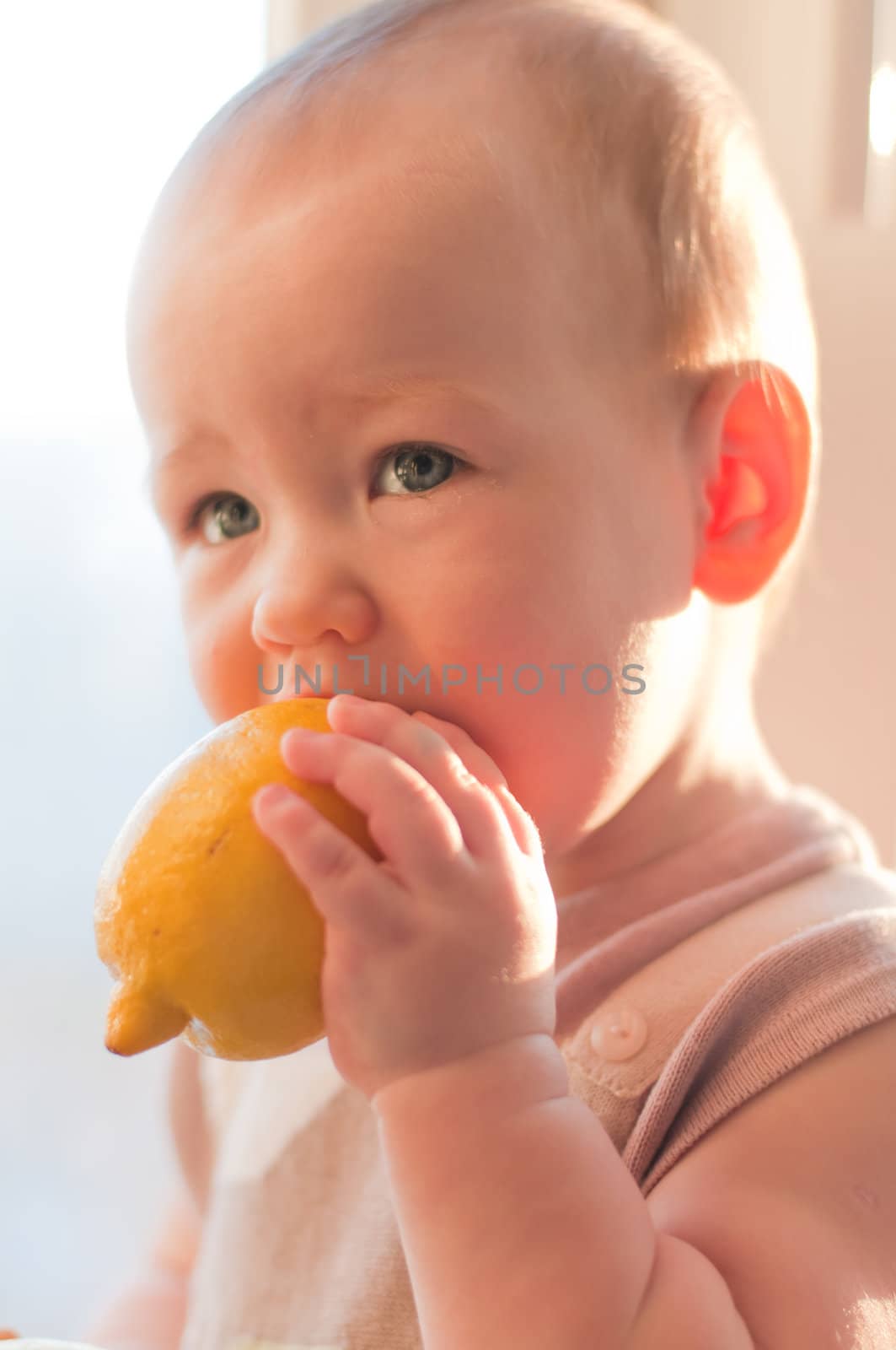 Baby girl with lemon in her hand