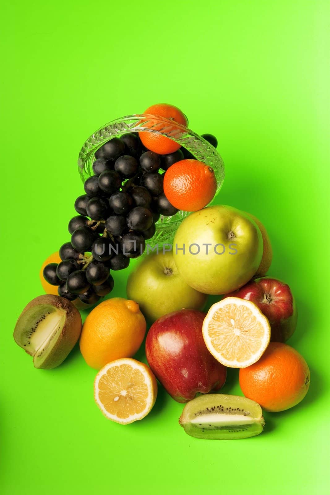 rich assortment of fruit consisting of apples, citron, grapes, kiwi on a green background