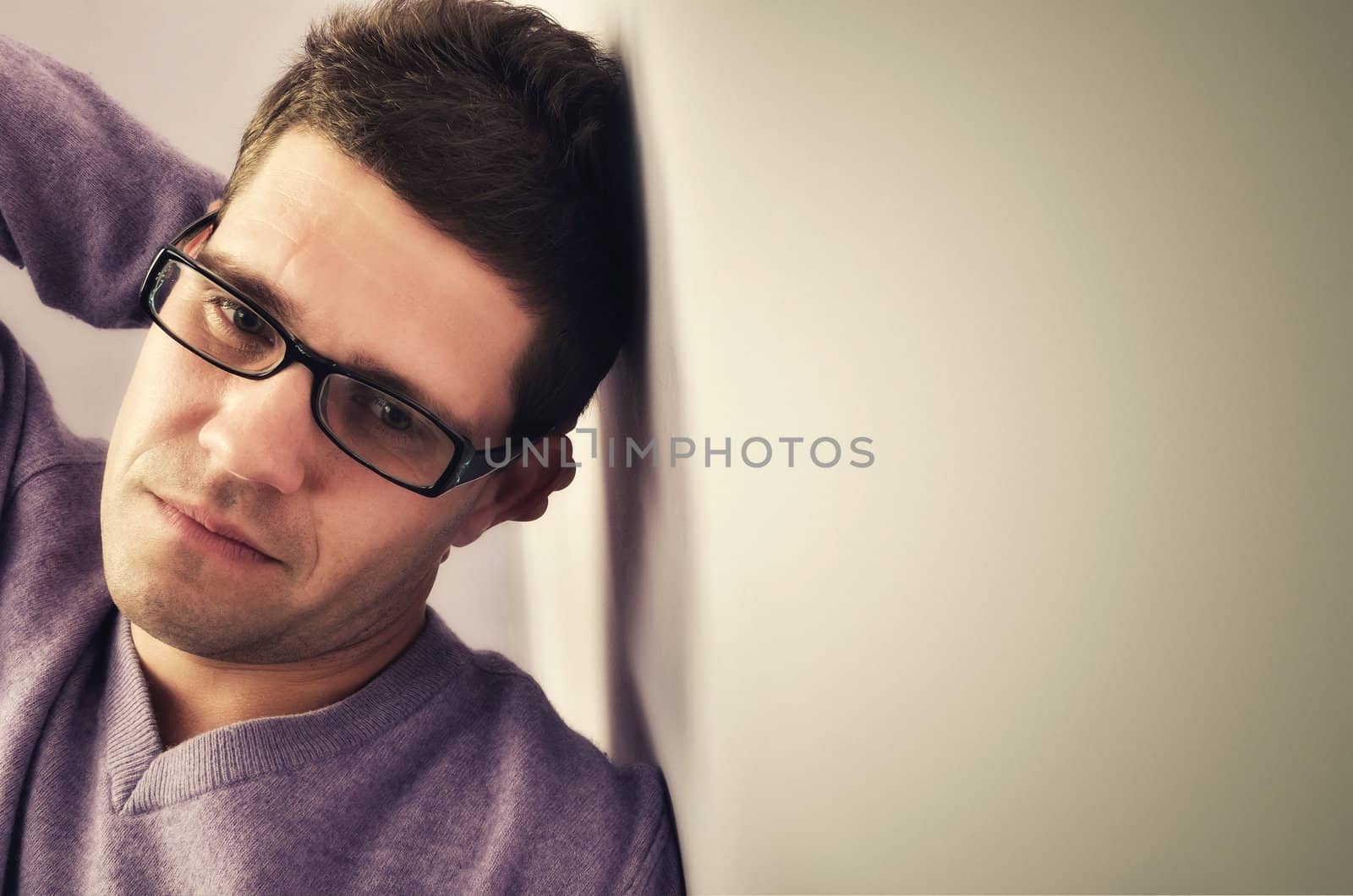 Young man lost in thought against a wall background