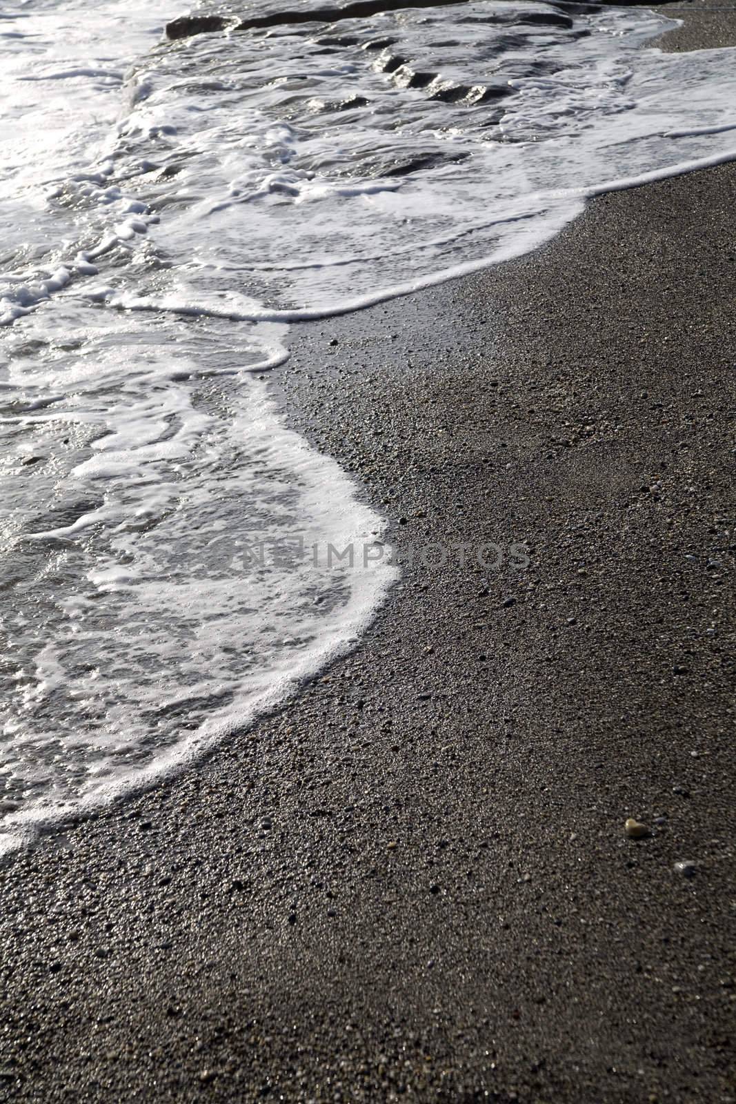 Sea foam formed from waves rolling on coast