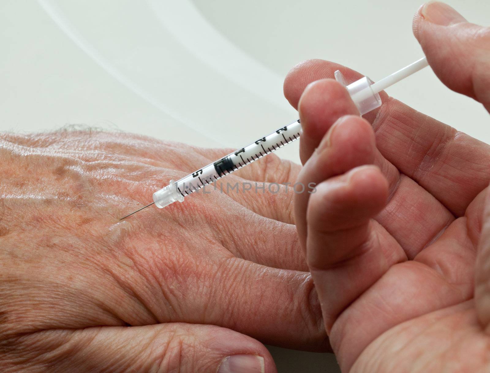 Injection into vein of senior man hand from small hypodermic needle