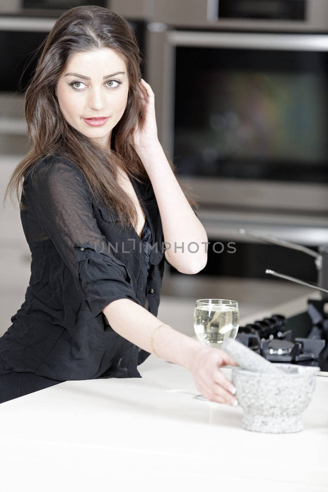 Beautiful young woman enjoying a glass of wine in her kitchen.