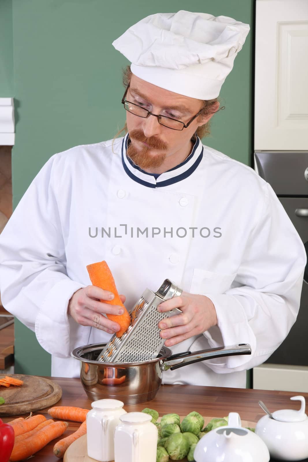 Young chef preparing lunch in kitchen by vladacanon