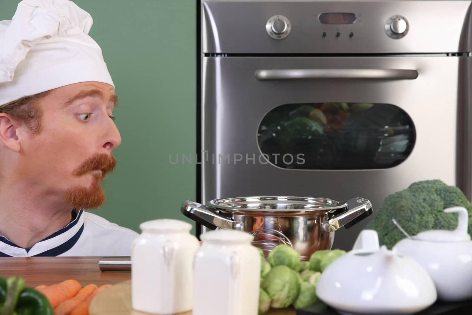 Funny young chef strange looking at pot