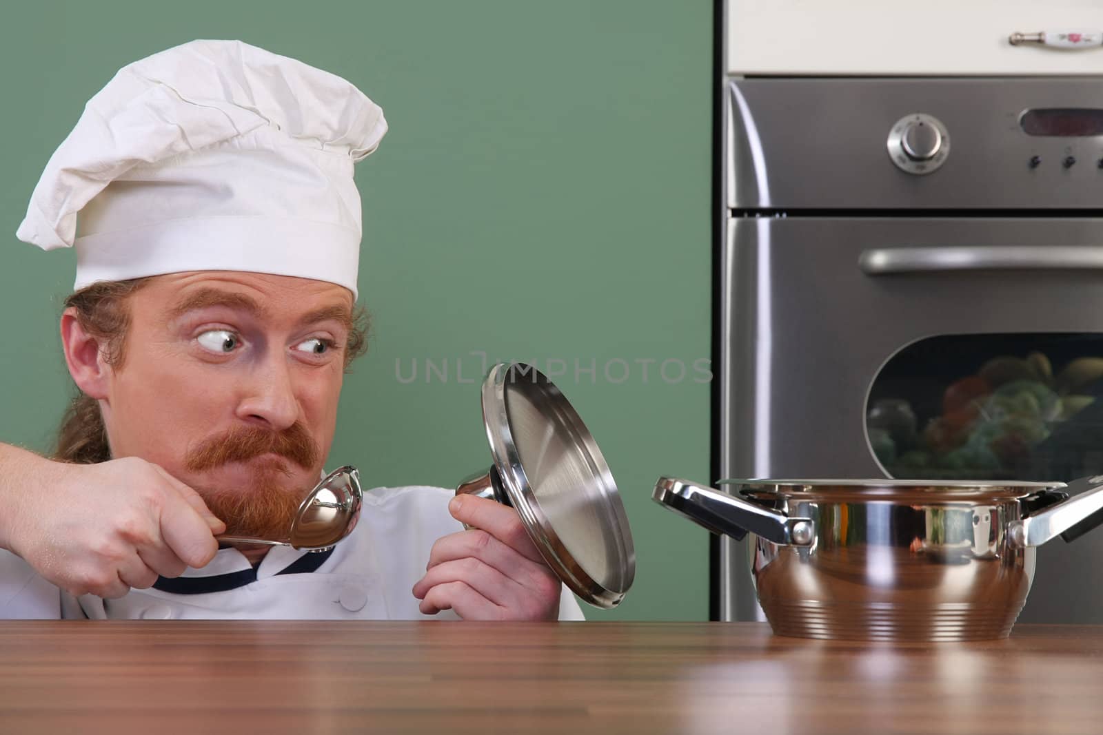 Funny young chef strange looking at pot