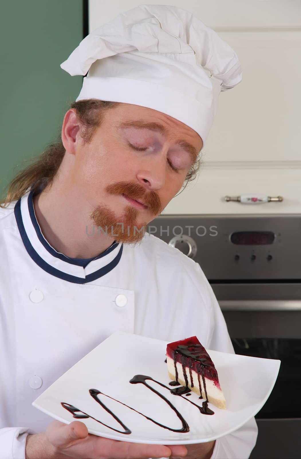 Funny young chef smelling a piece of cake with chocolate sauce