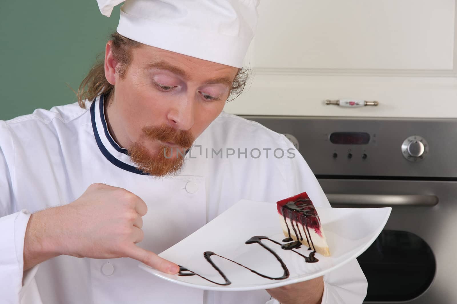 Funny young chef strange looking at piece of cake with chocolate sauce