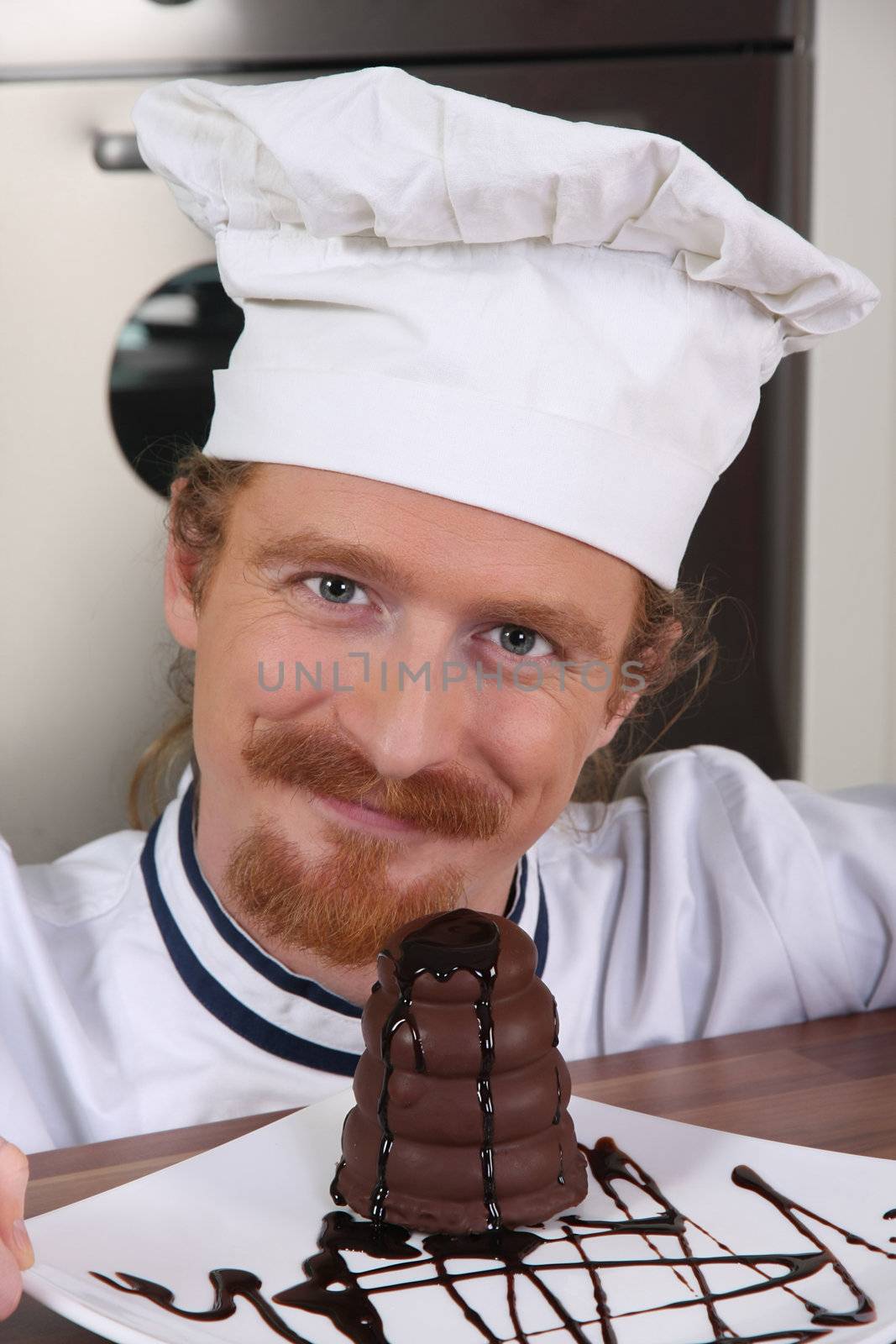 Young chef with piece of cake with chocolate sauce 