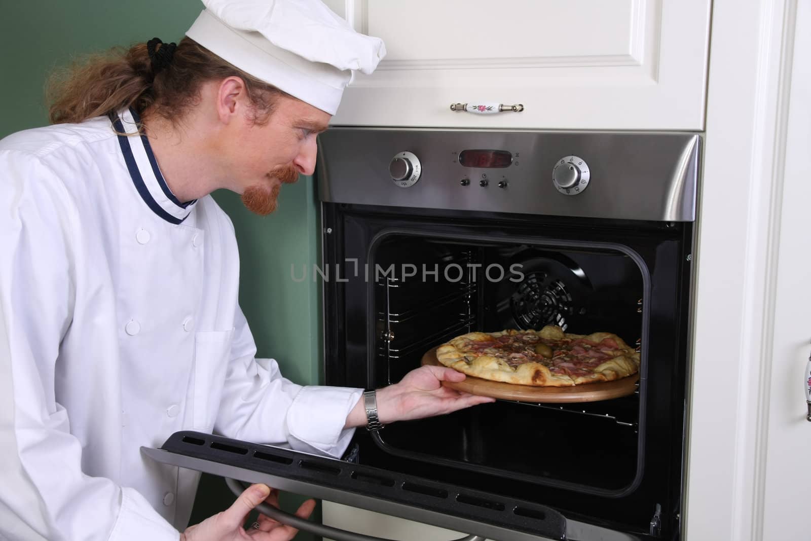 Young chef prepared italian pizza in kitchen by vladacanon