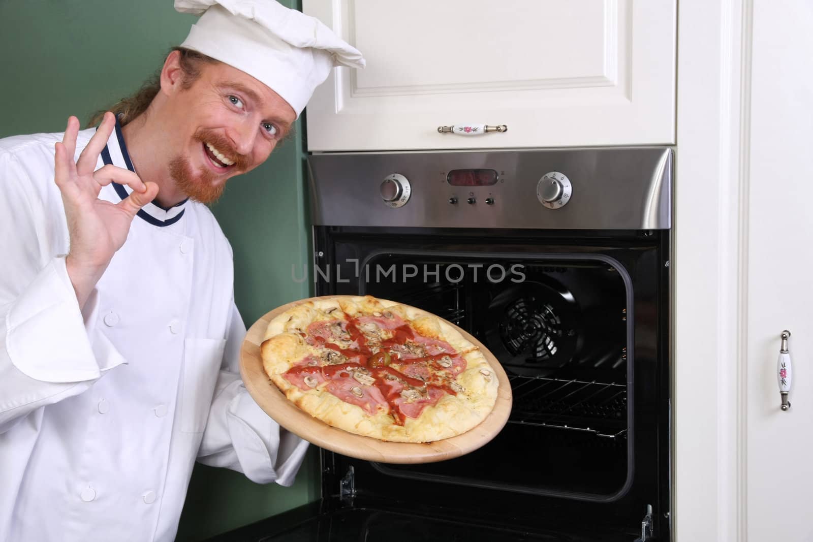 young chef with italian pizza in kitchen  by vladacanon