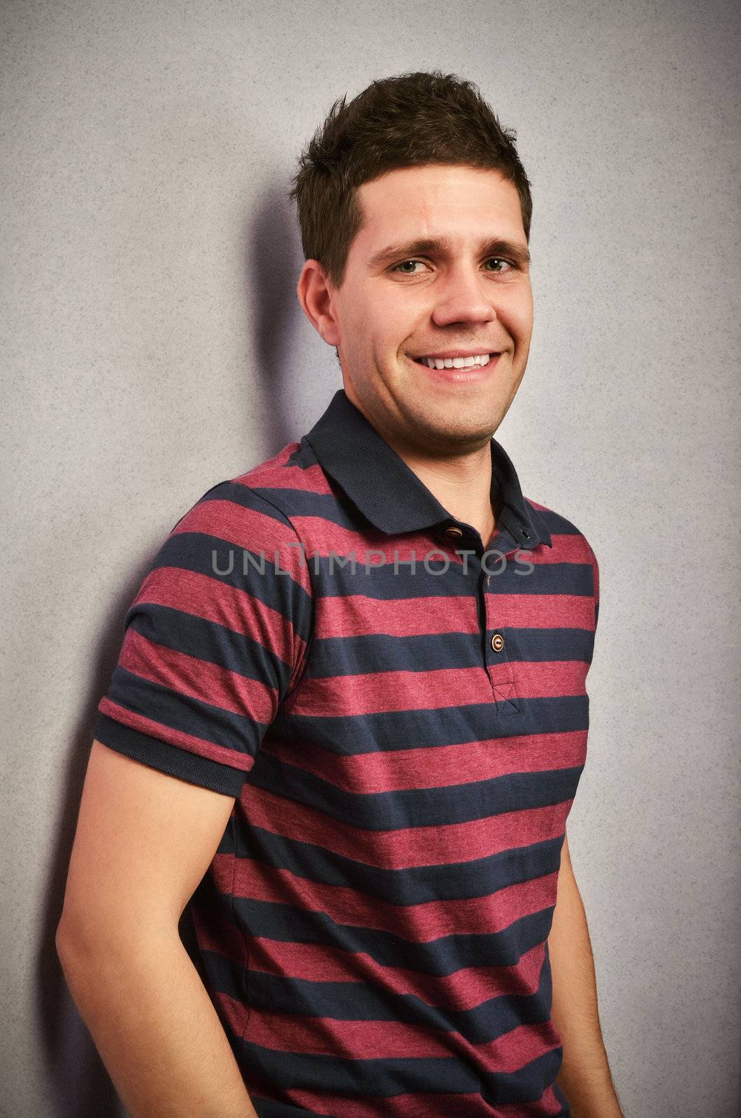 Cool teenager smiling and looking at camera against a wall