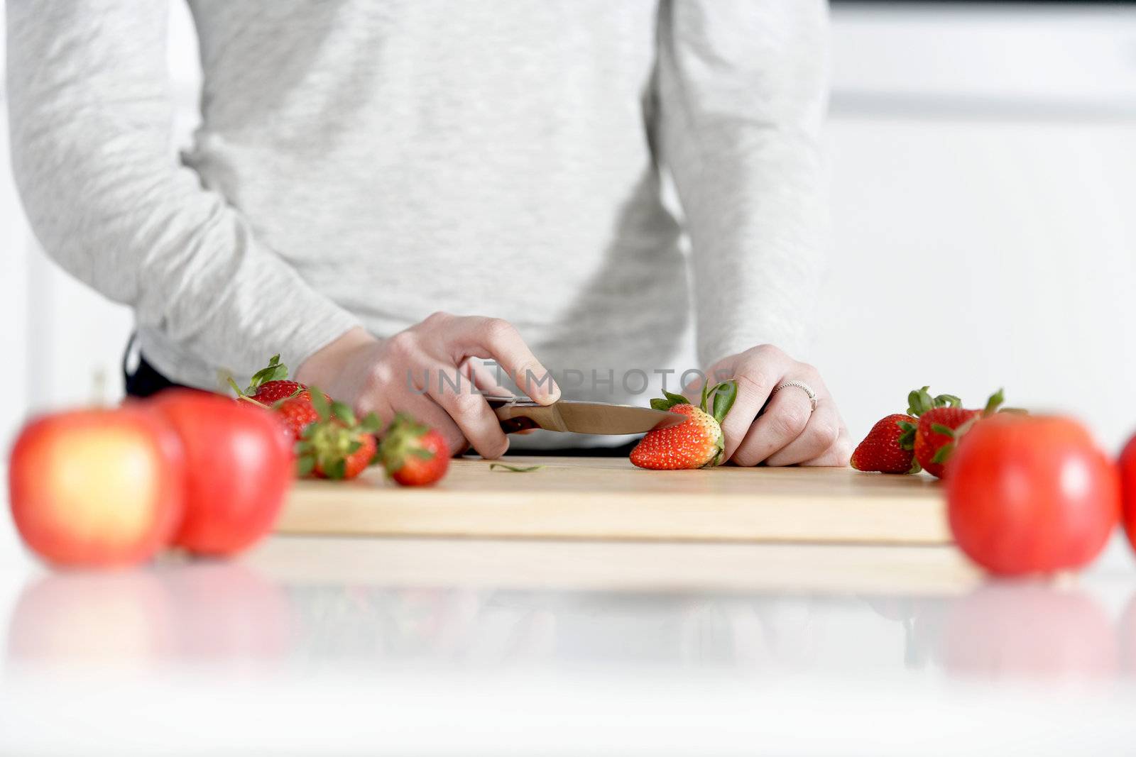 Woman cutting up fruit by studiofi