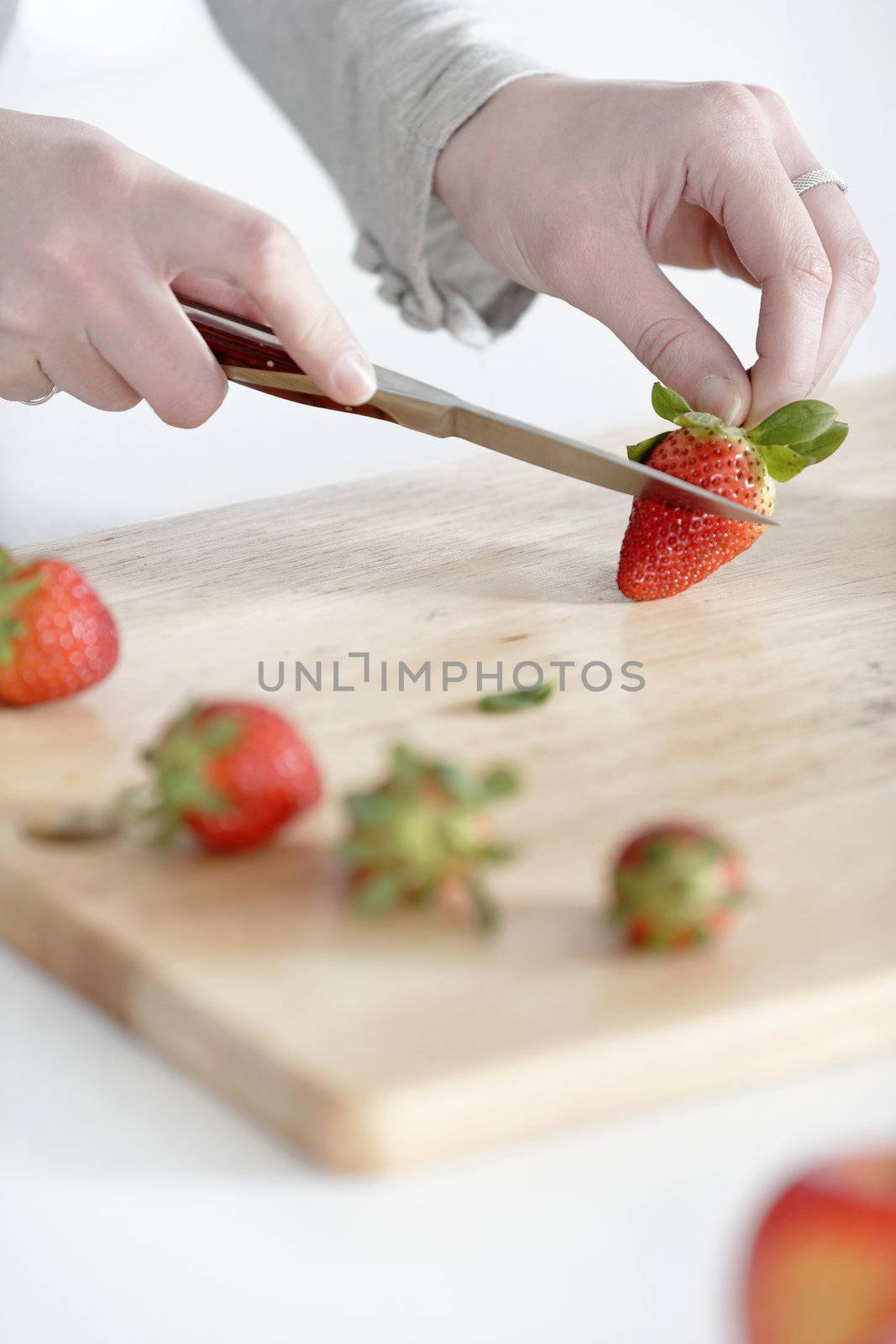 Beautiful young woman preparing strawberries in her white kitchen