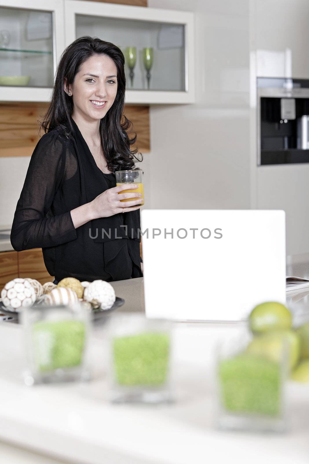 Woman using her laptop in kitchen by studiofi