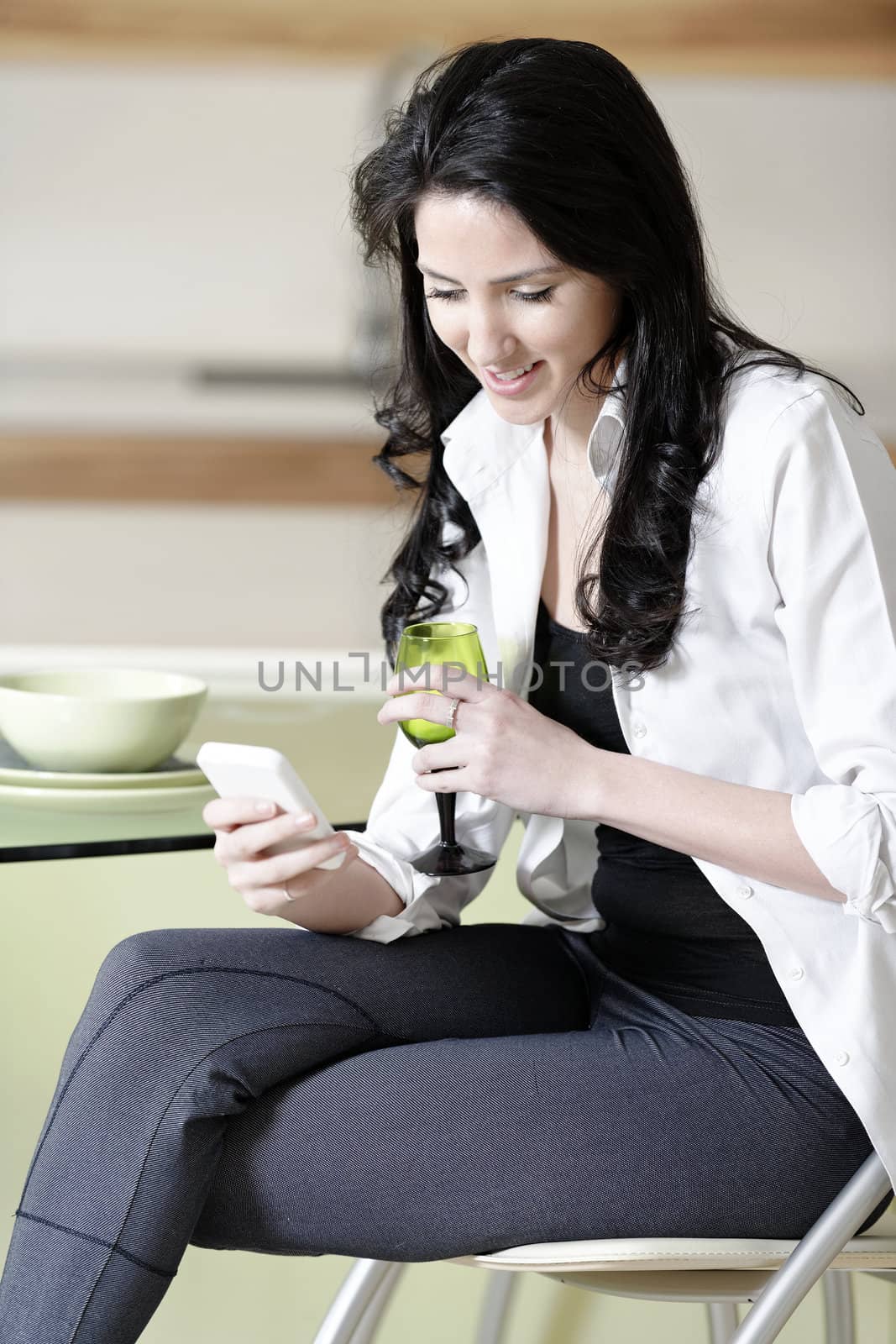 Beautiful young woman chatting on her mobile phone in her kitchen