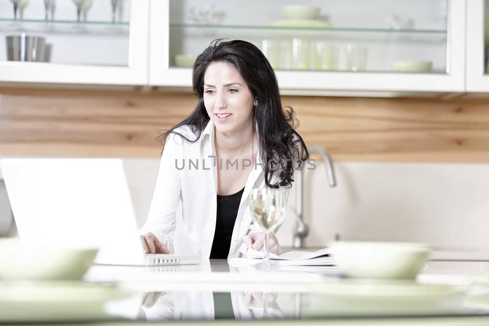 Woman using her laptop in kitchen by studiofi