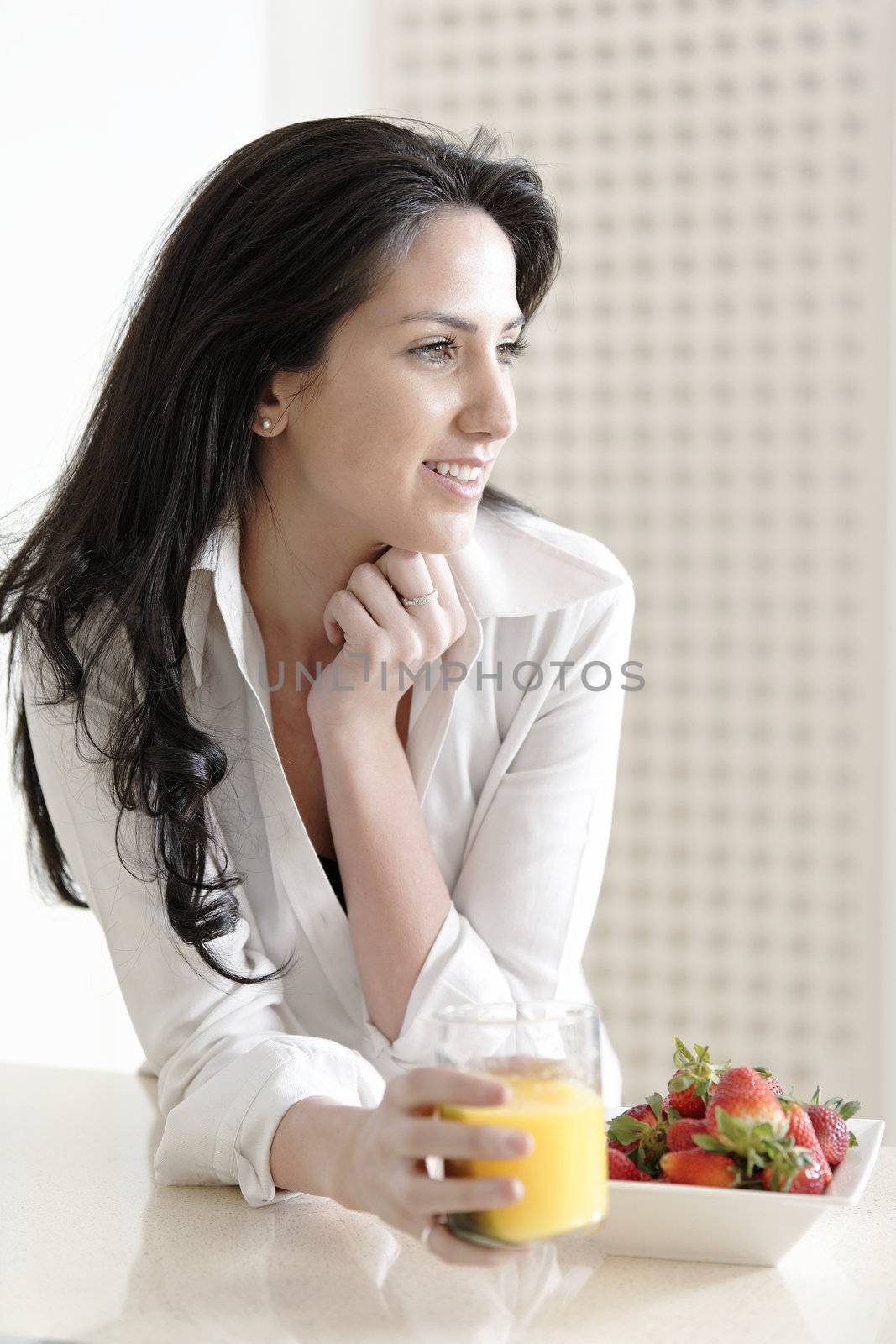 Attractive young woman enjoying a fresh fruit breakfast at home.