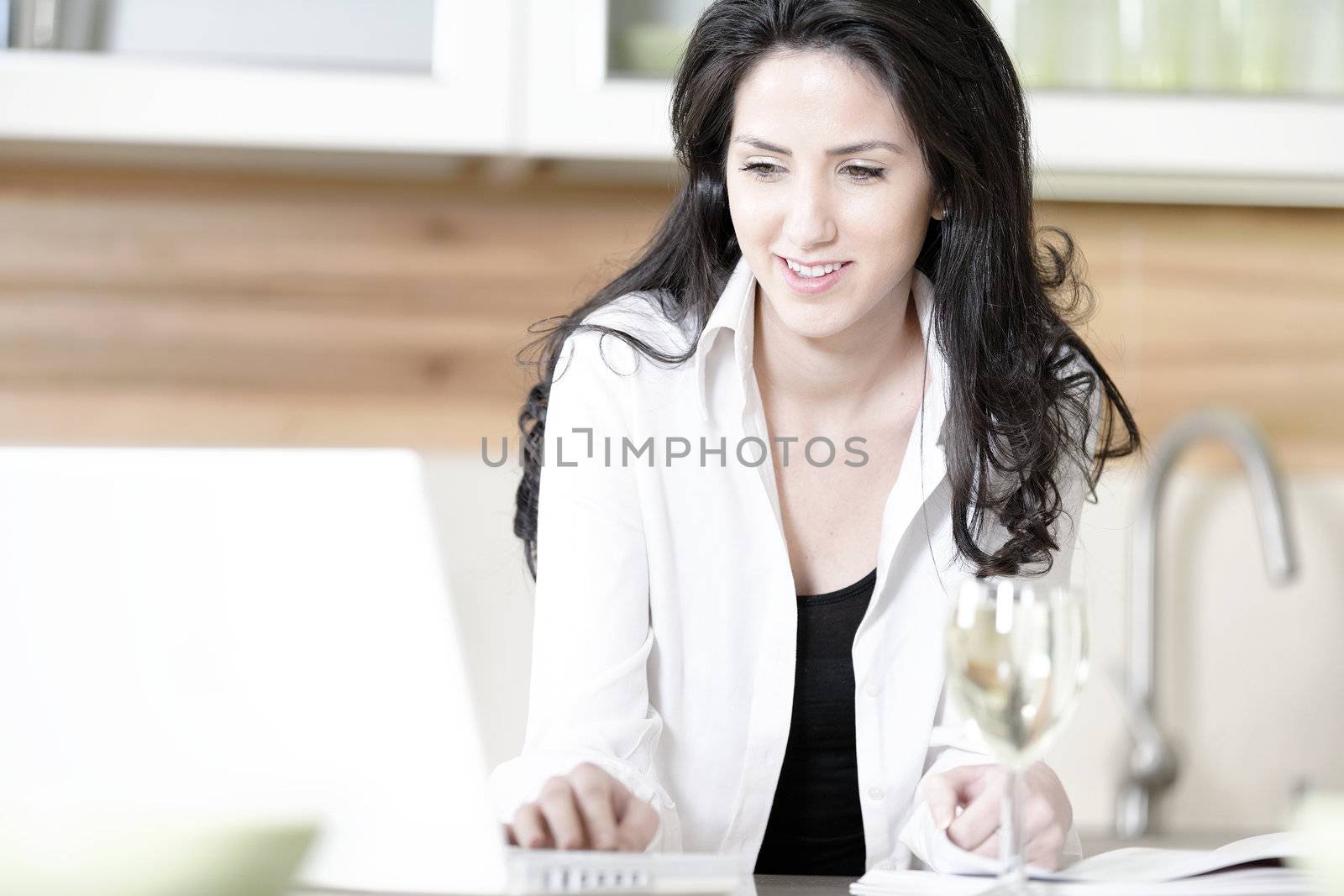 Attractive young woman using her laptop in the kitchen