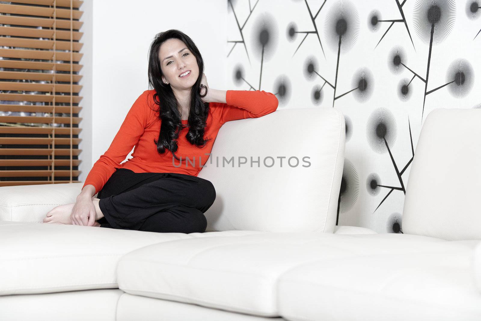 Beautiful woman relaxing on a white sofa in an elegant living room.