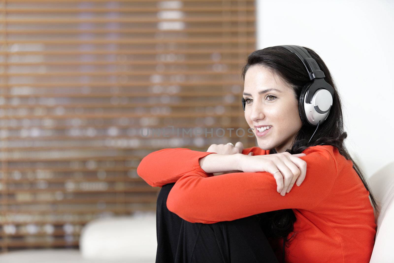 Attractive woman sat on a white sofa listening to music