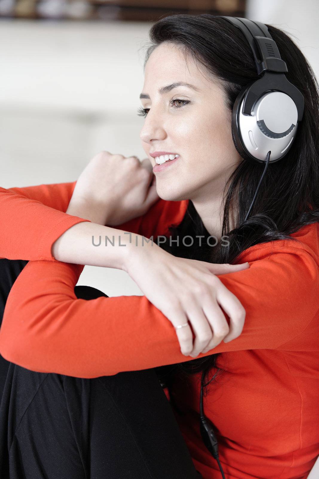 Attractive woman sat on a white sofa listening to music