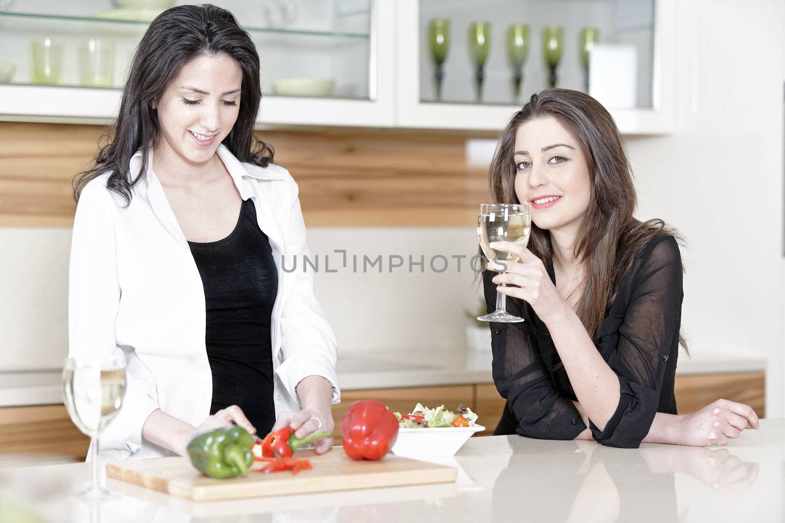 Two friends in a kitchen cooking by studiofi