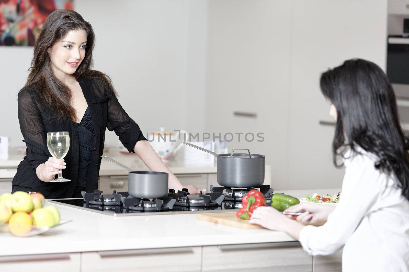 Two friends in a kitchen catching up preparing dinner.