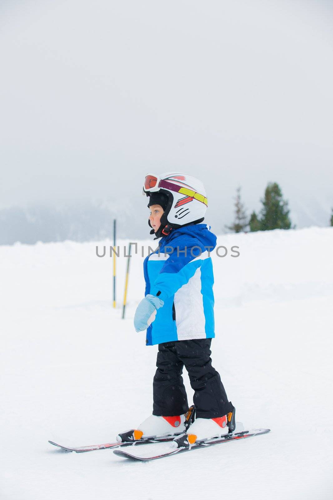 Junior skier. Little cute boy in a ski outfit rises in ski school on hill