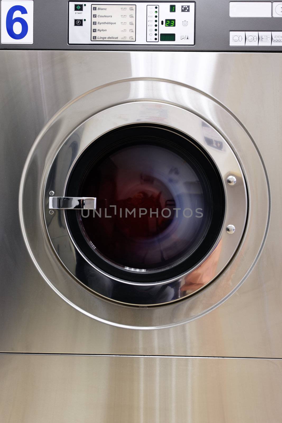 A row of industrial washing machines in a public laundromat 