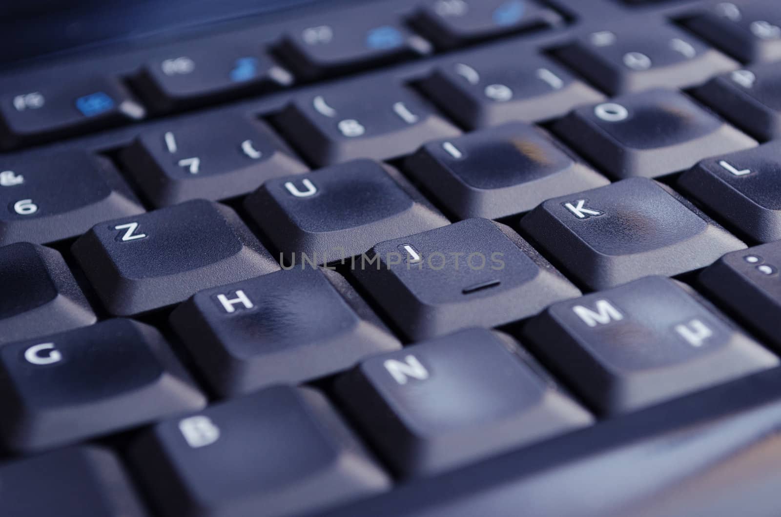 A black keyboard illuminated by the computer screen. Selective Focus.