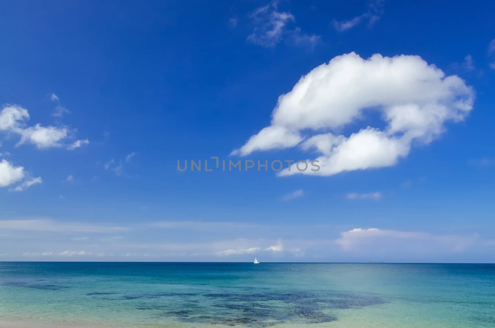 Ocean day landscape with blue cloudy sky and sailboat