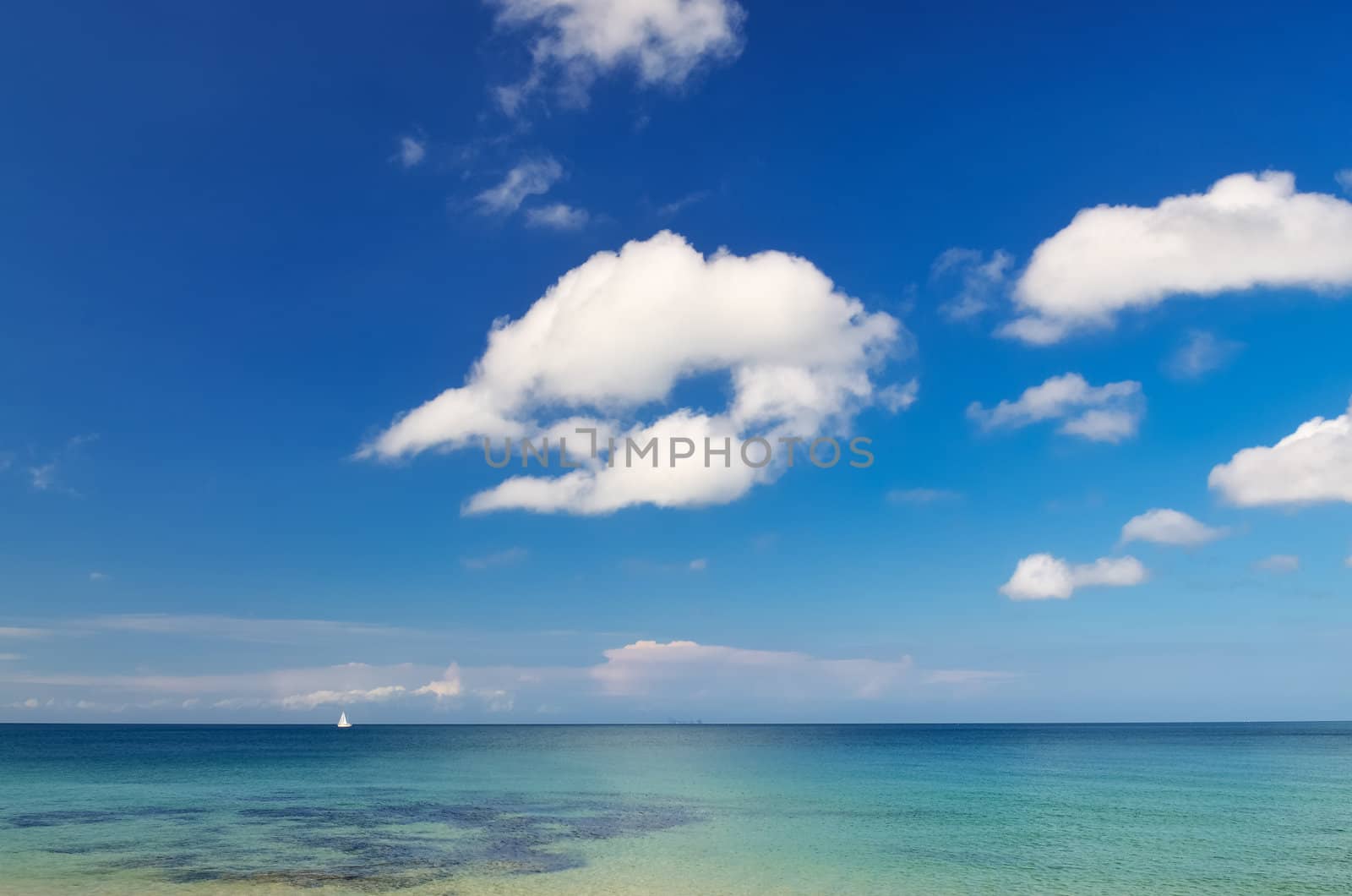 Ocean day landscape with blue cloudy sky and little sailboat