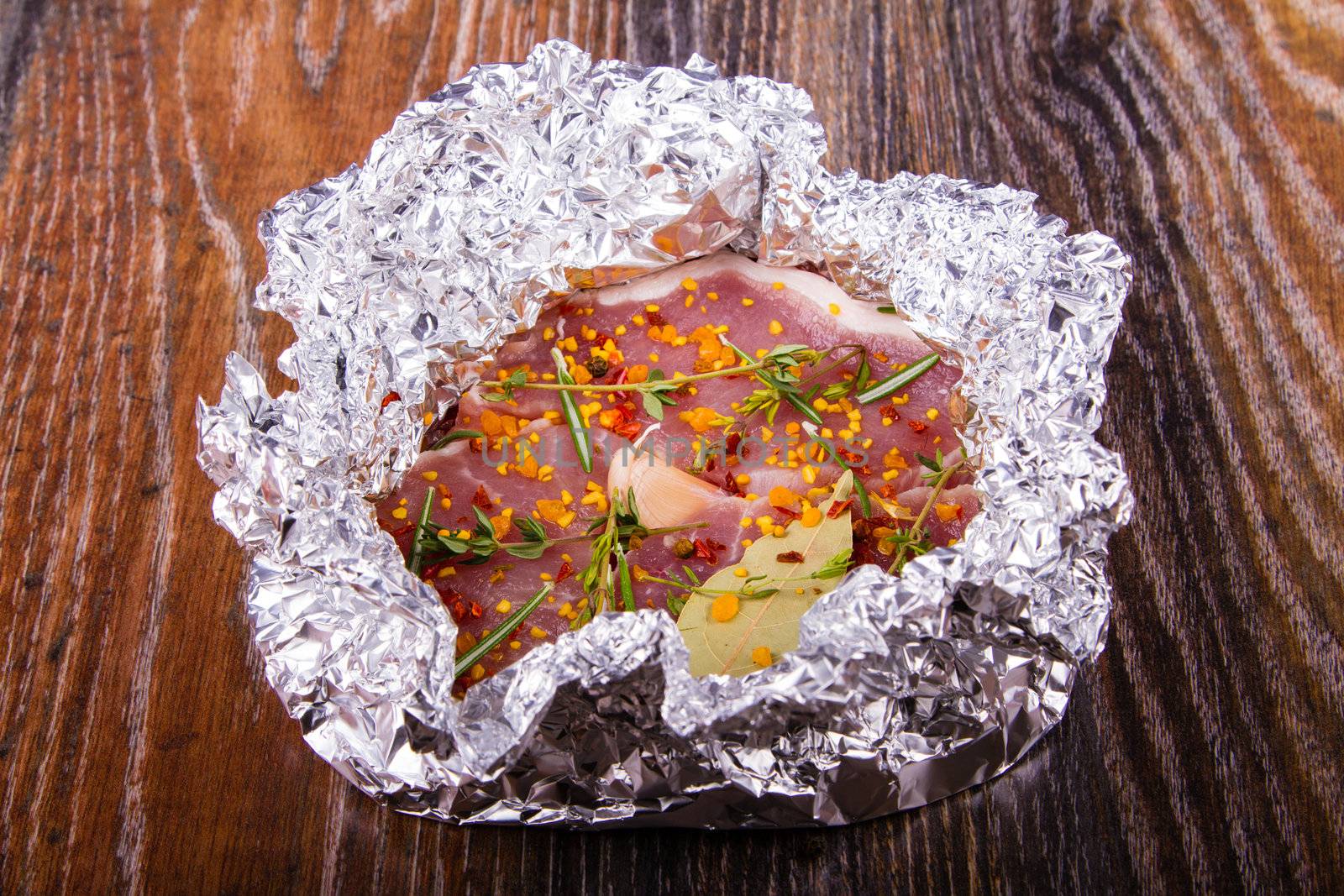 Raw fresh meat in foil with condiments