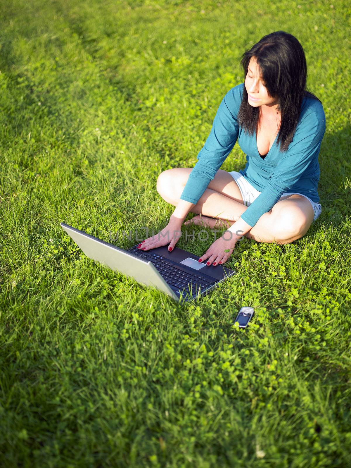 Young woman using laptop in park by adamr