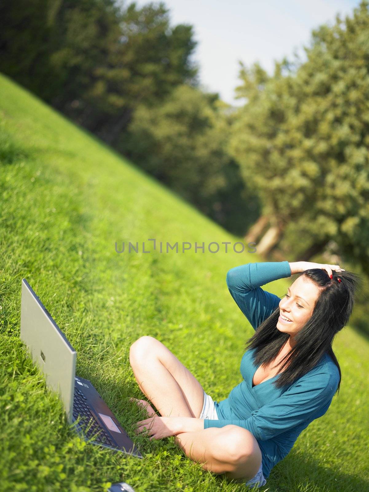 Young woman using laptop in park by adamr