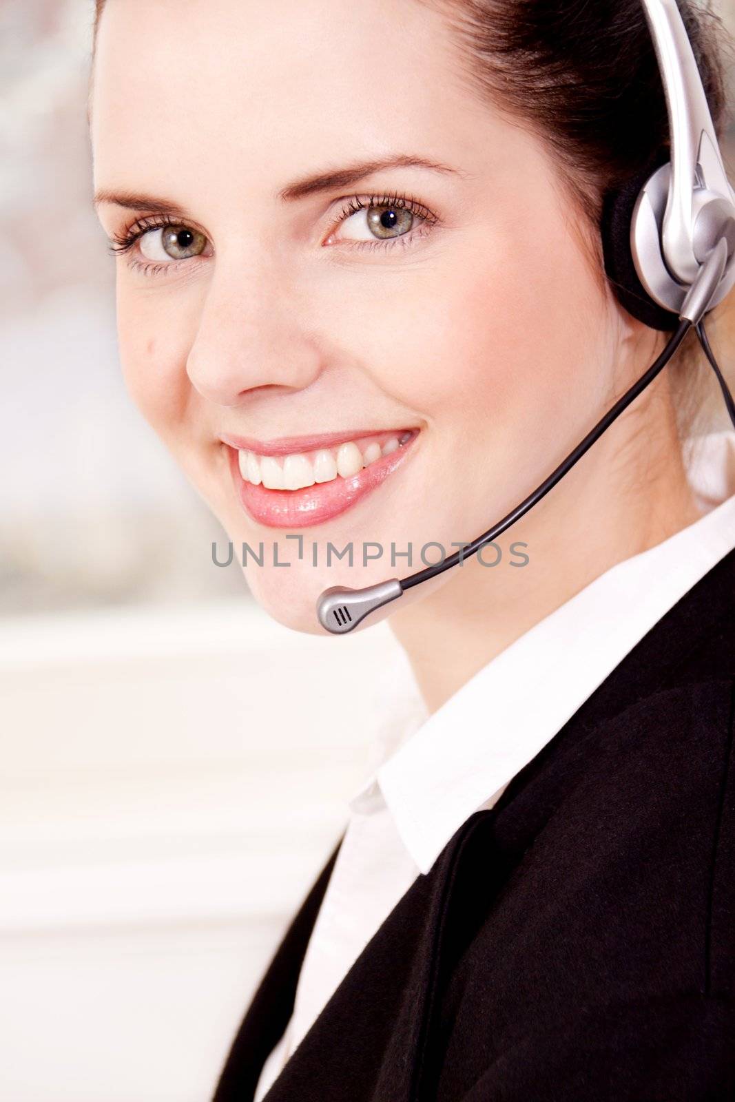 smiling young female callcenter agent with headset in office