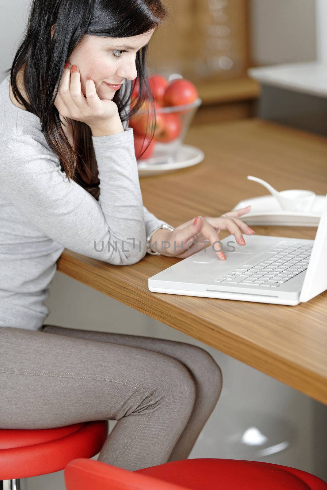 Woman using her laptop at home by studiofi