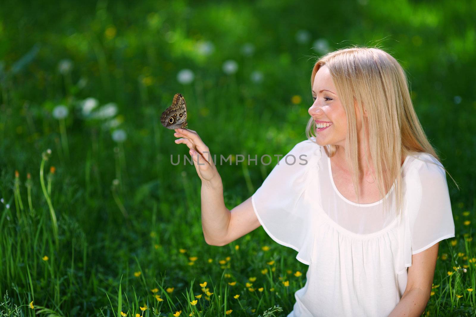 Woman playing with a butterfly on green grass