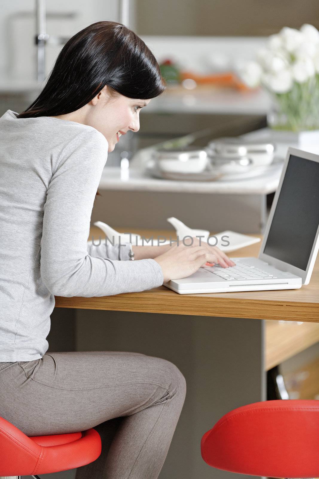 Woman using her laptop at home by studiofi