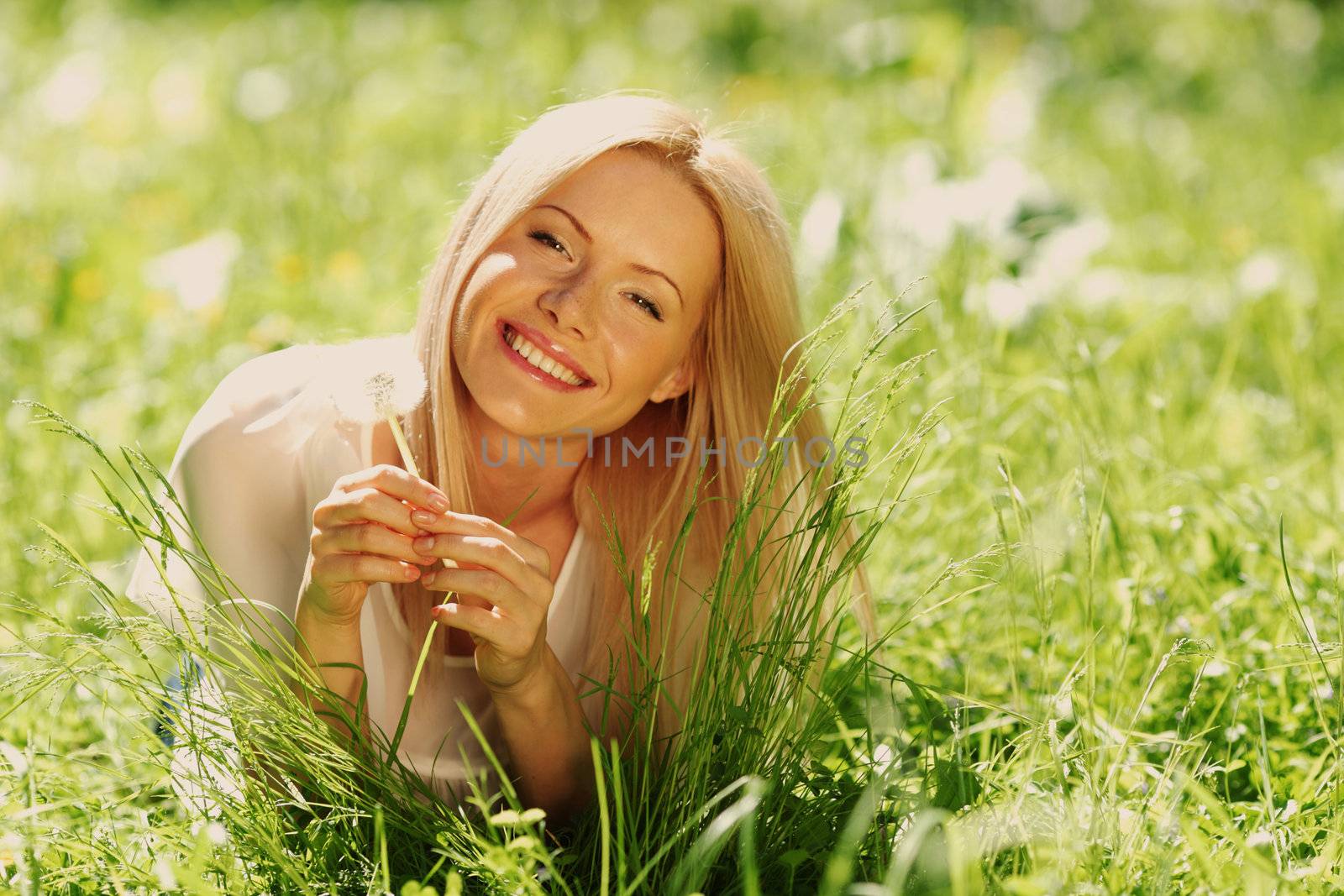 girl with a dandelion in his hand lying on the grass