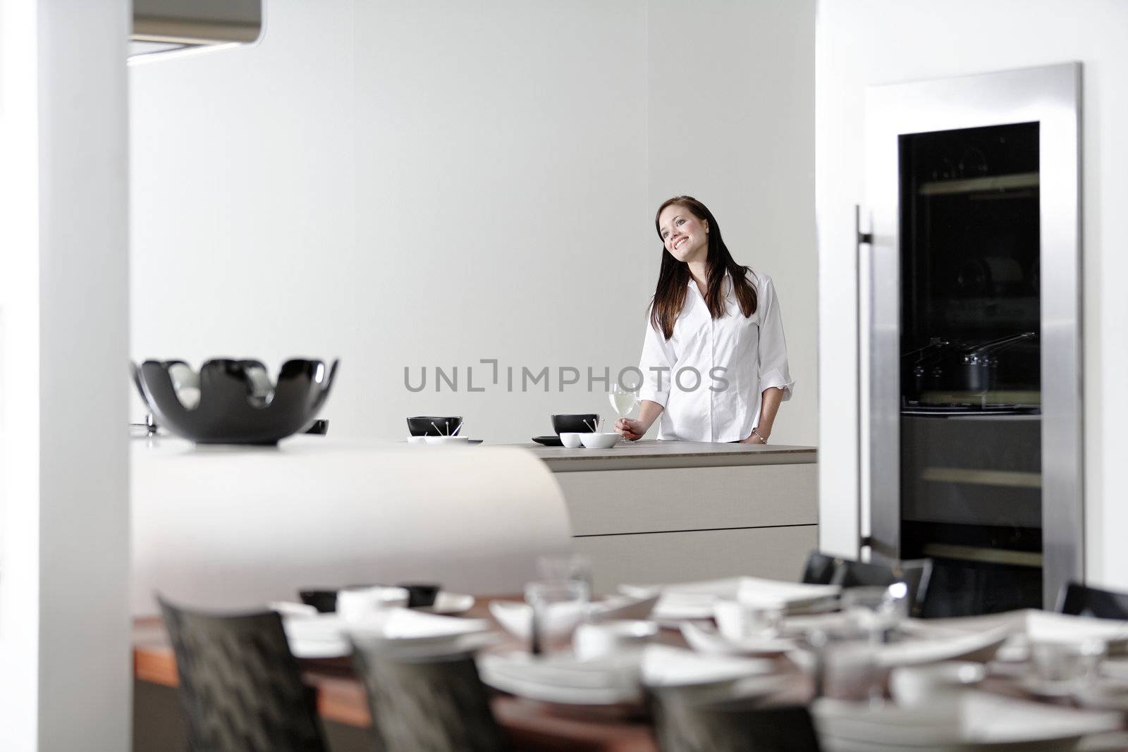 Beautiful young woman relaxing in her elegant white kitchen