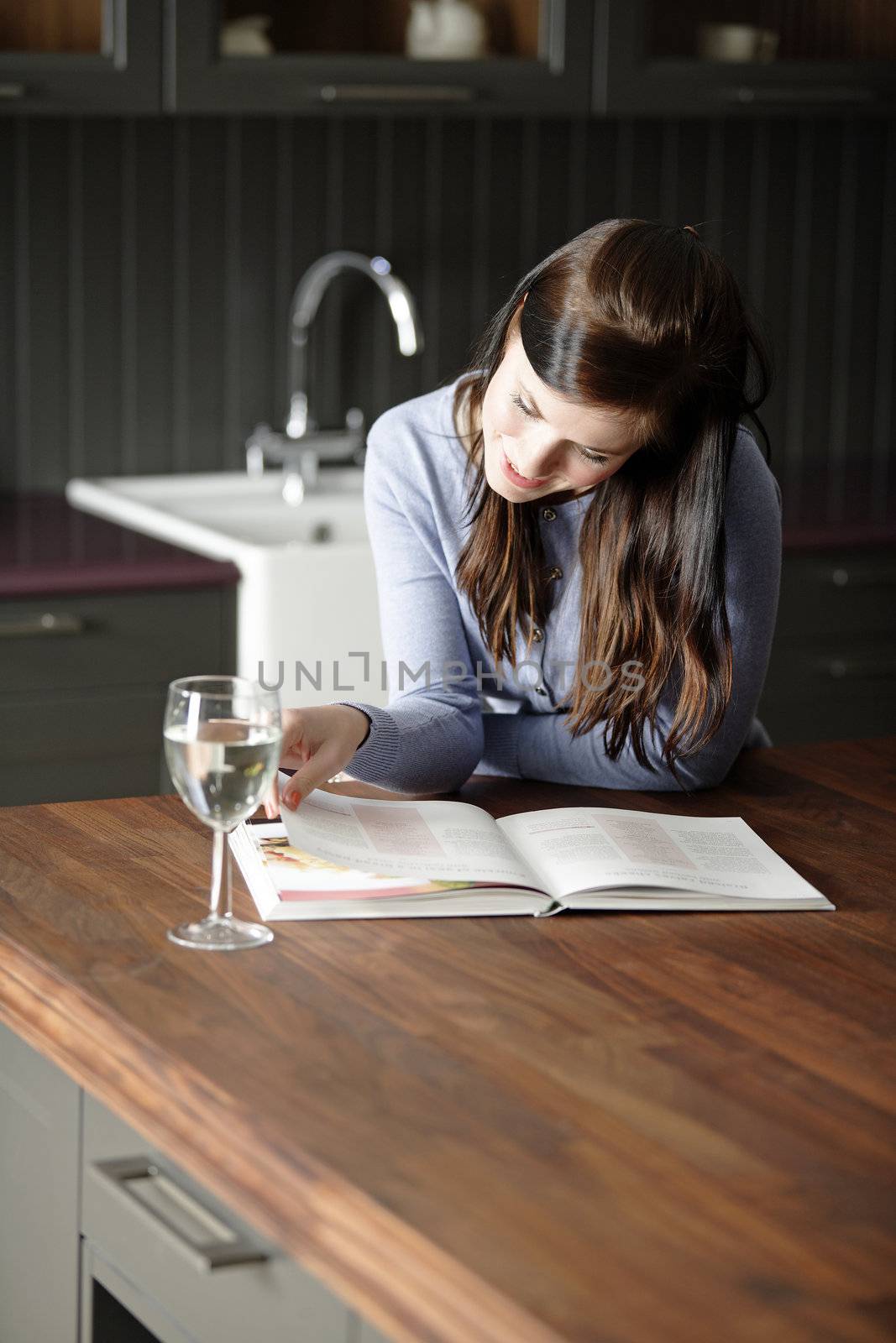 Woman reading a cookery book by studiofi