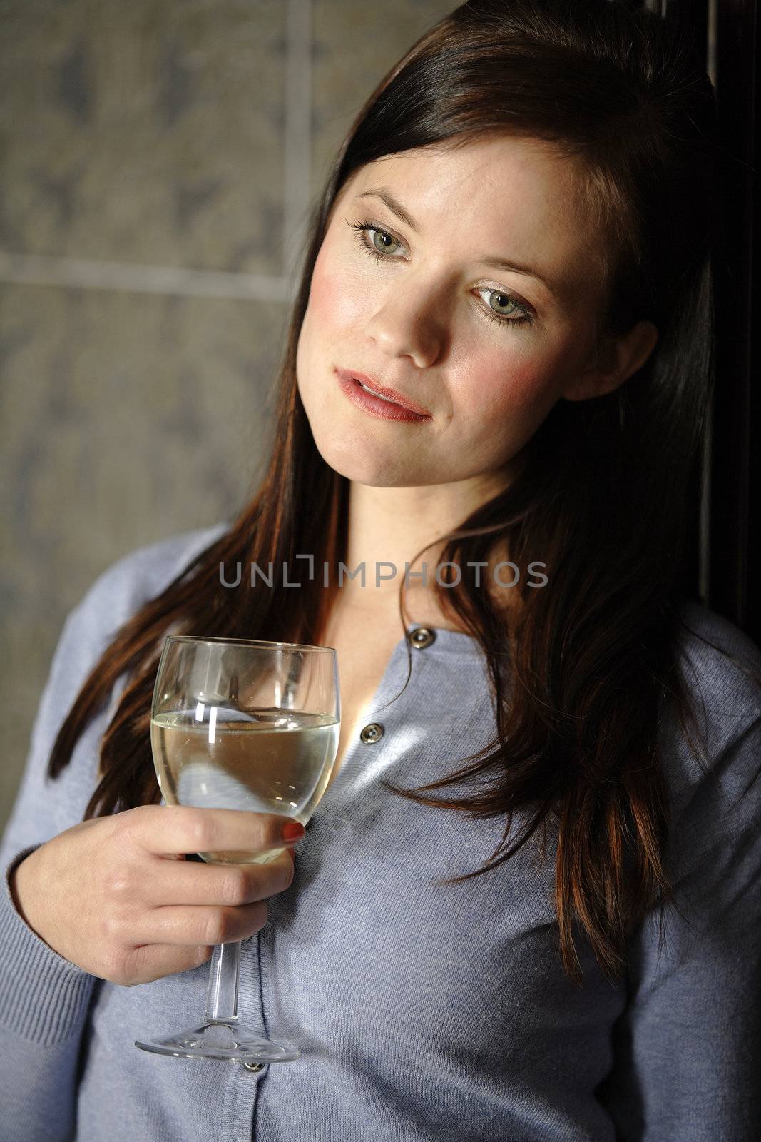 Attractive young woman enjoying a glass of wine in her kitchen.