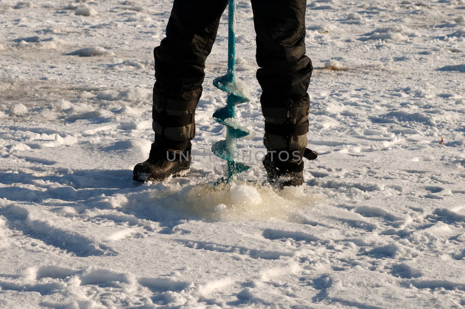 Man in cold winter day make ice-hole for winter fishing