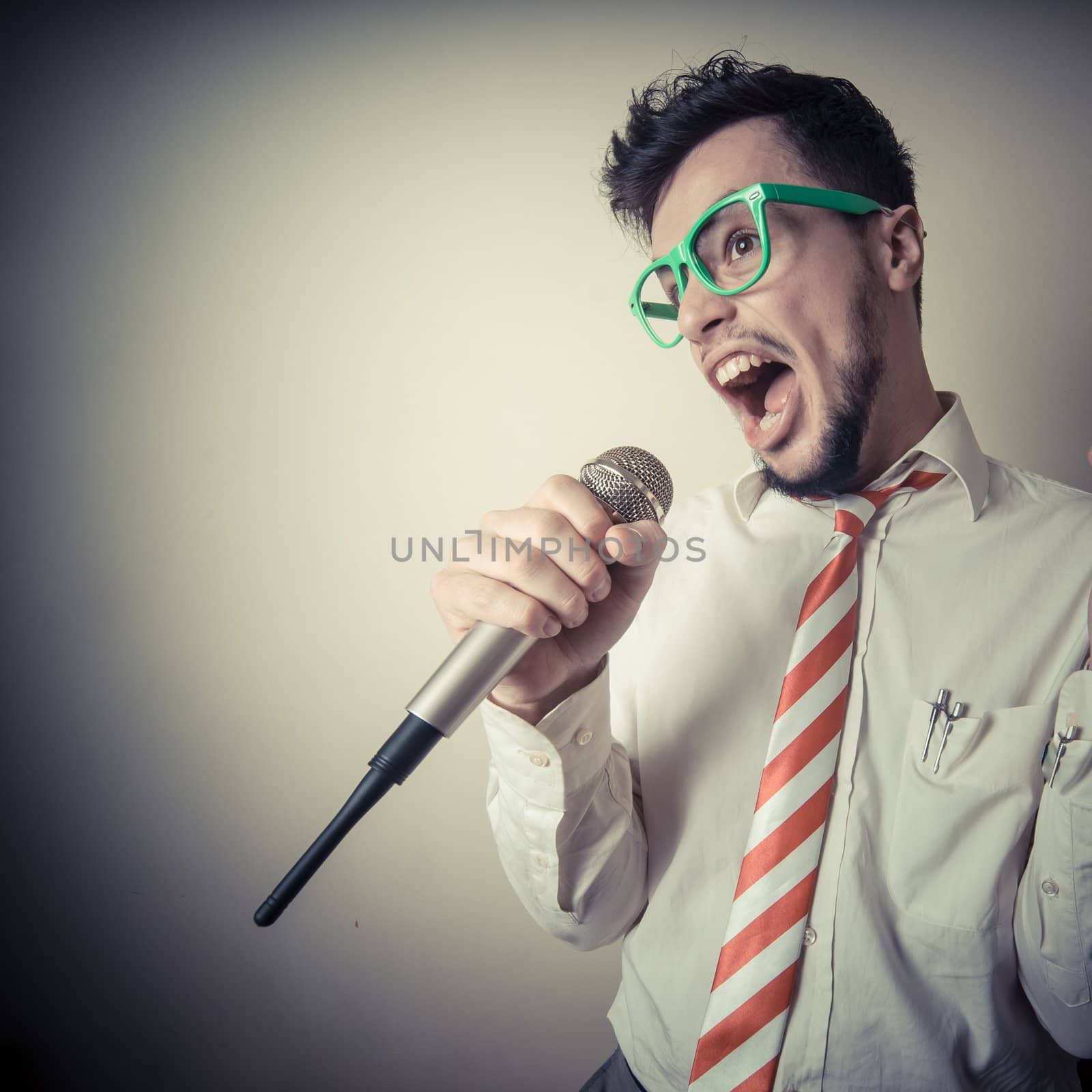 funny stylish businessman singing on gray background