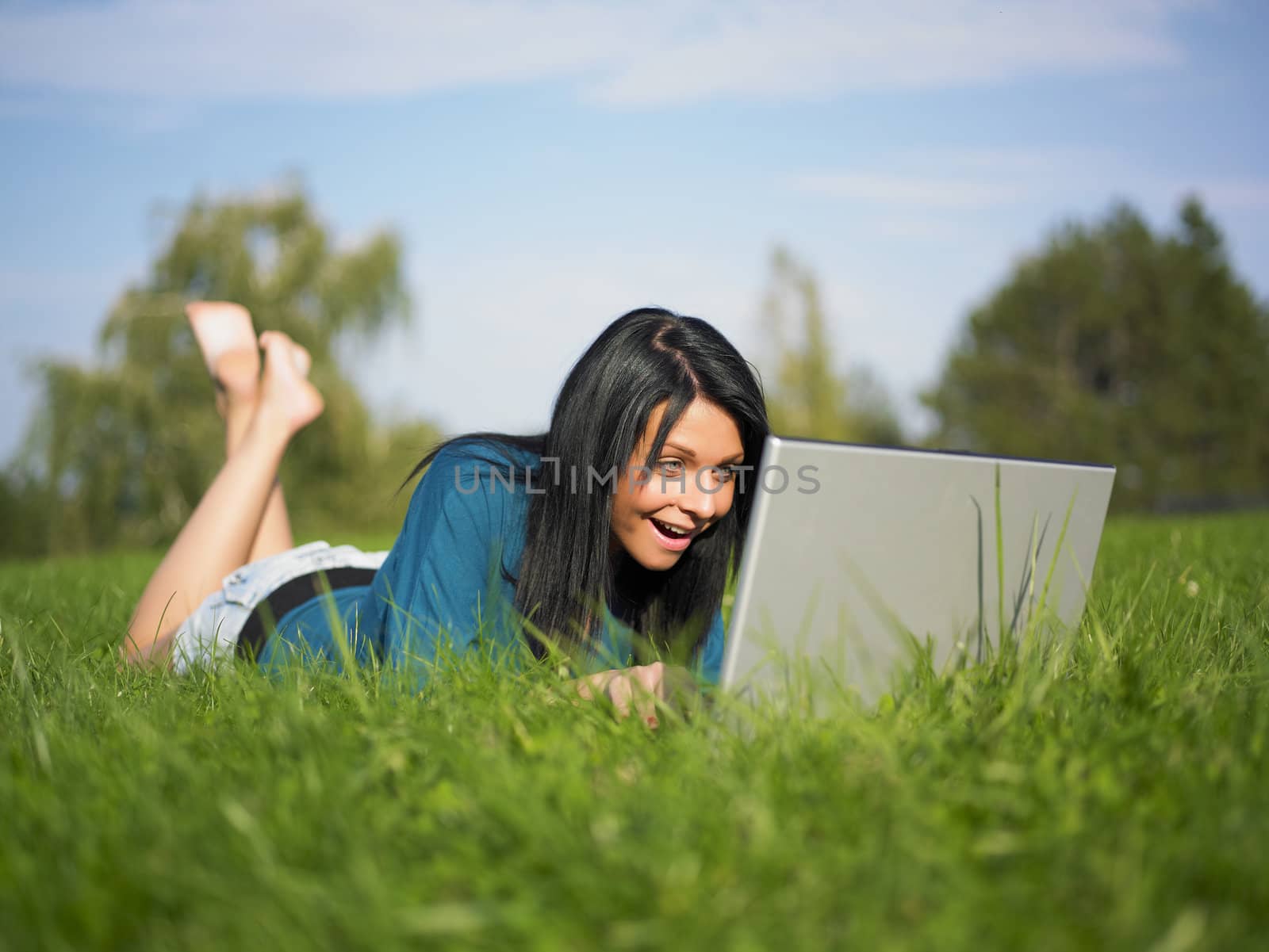 Young woman using laptop in park by adamr